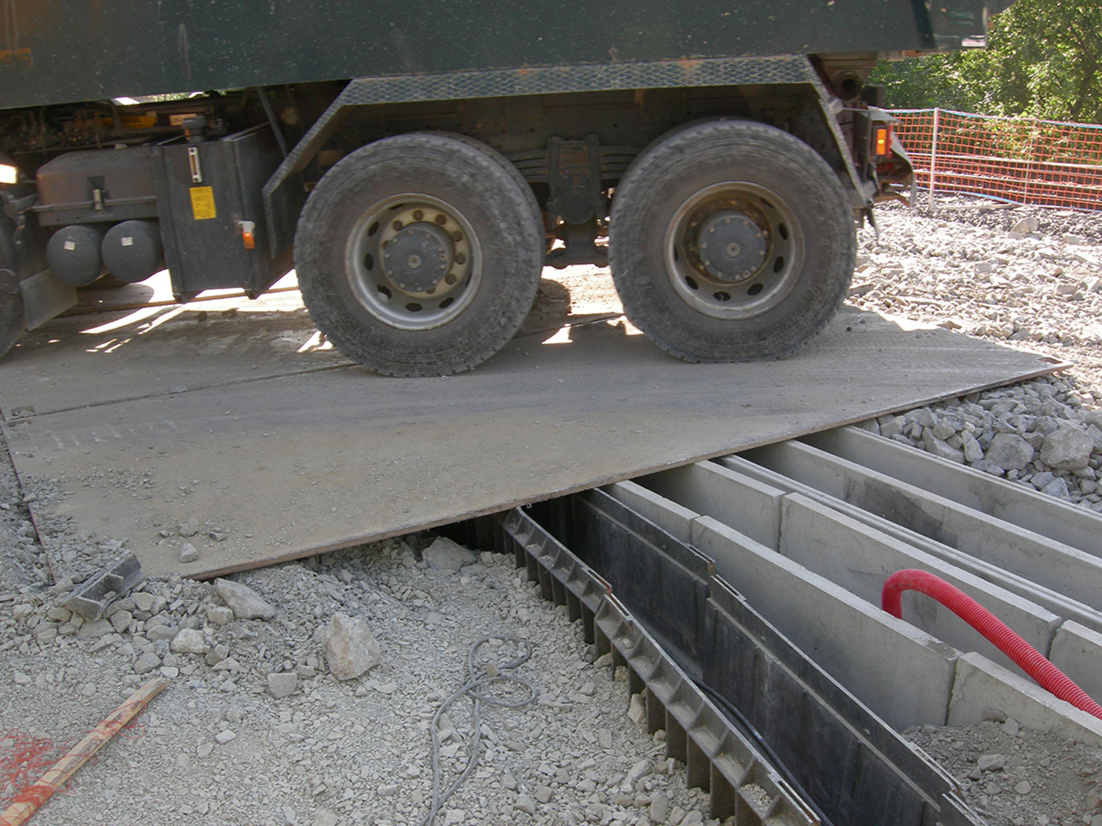 Stålplate lagt rett på kabelkanaler, tungt kjøretøy på toppen.