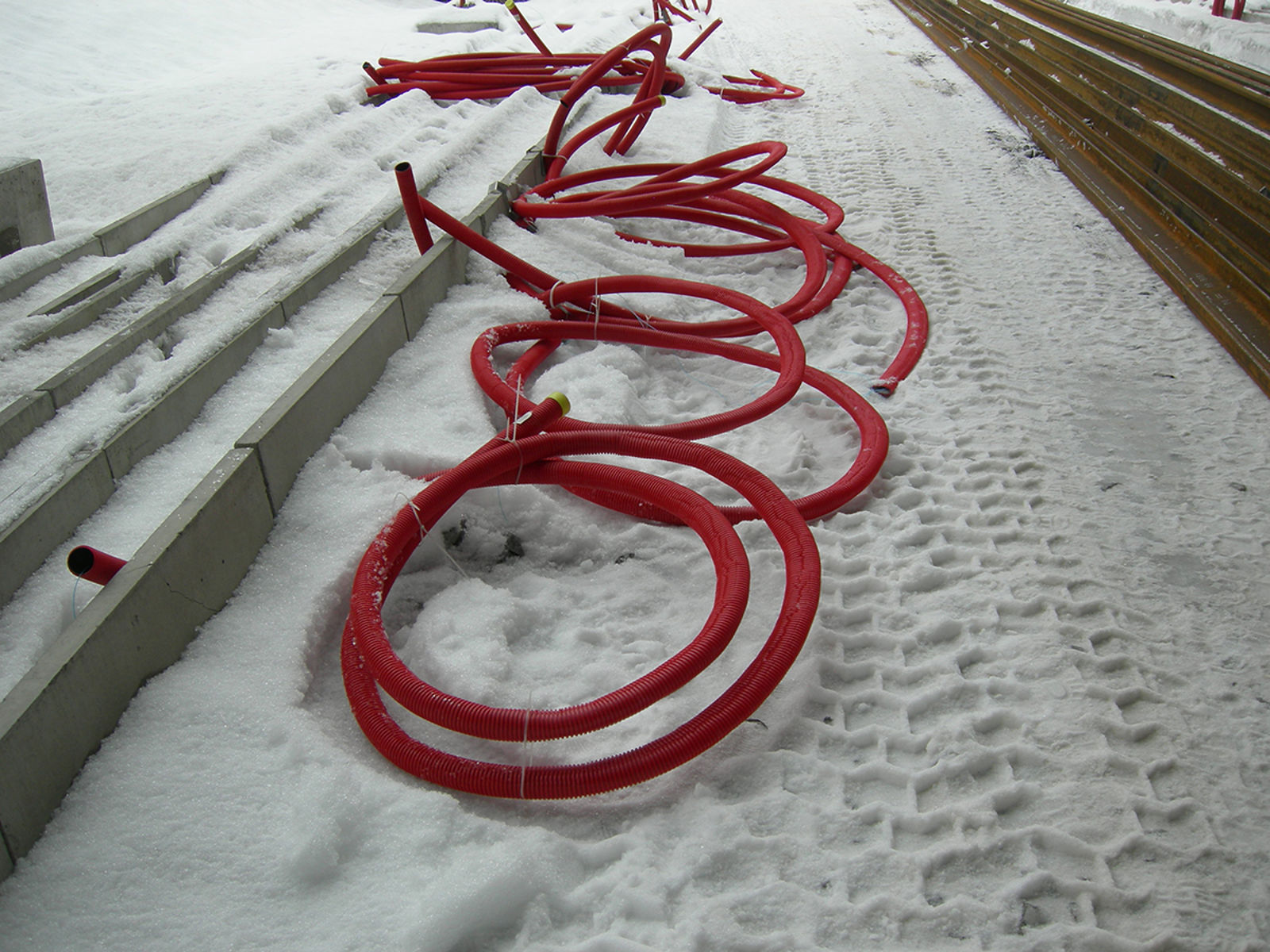 Flate trekkerør lagt ut på snødekket underlag med kabelkanaler.
