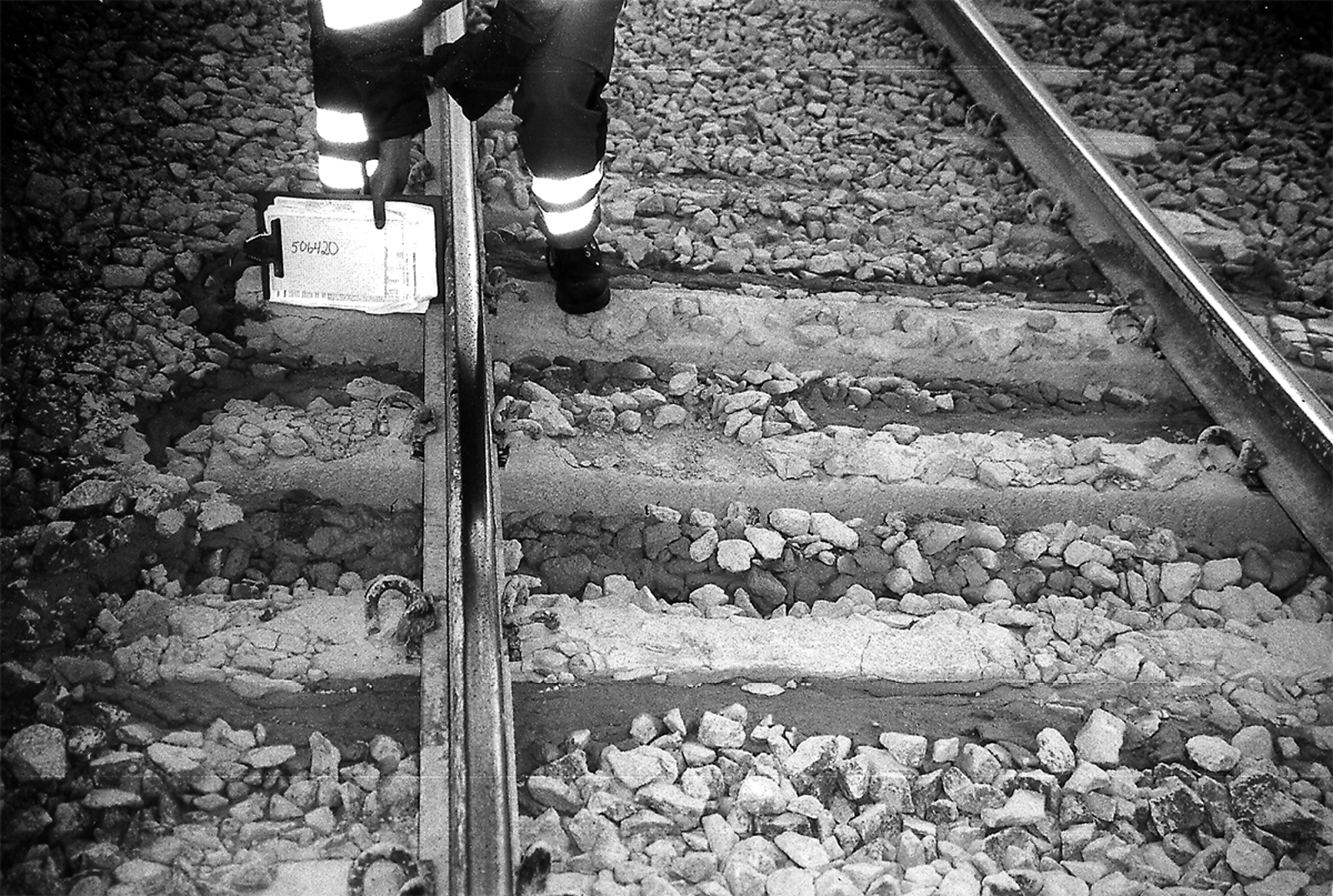 Banearbeider peker på sviller der pukken er vasket bort og svilleoverflaten er synlig.