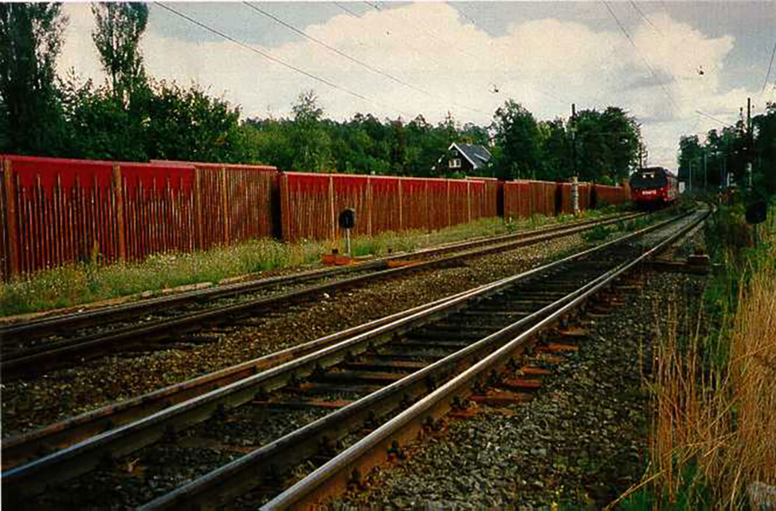 Rød støyskjerm langs jernbanespor mellom Skøyen og Lysaker.