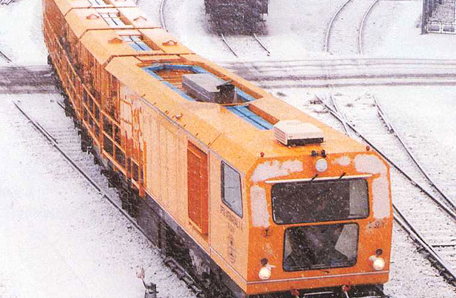 32-steners slipetog fra Speno på jernbanespor i snøvær.