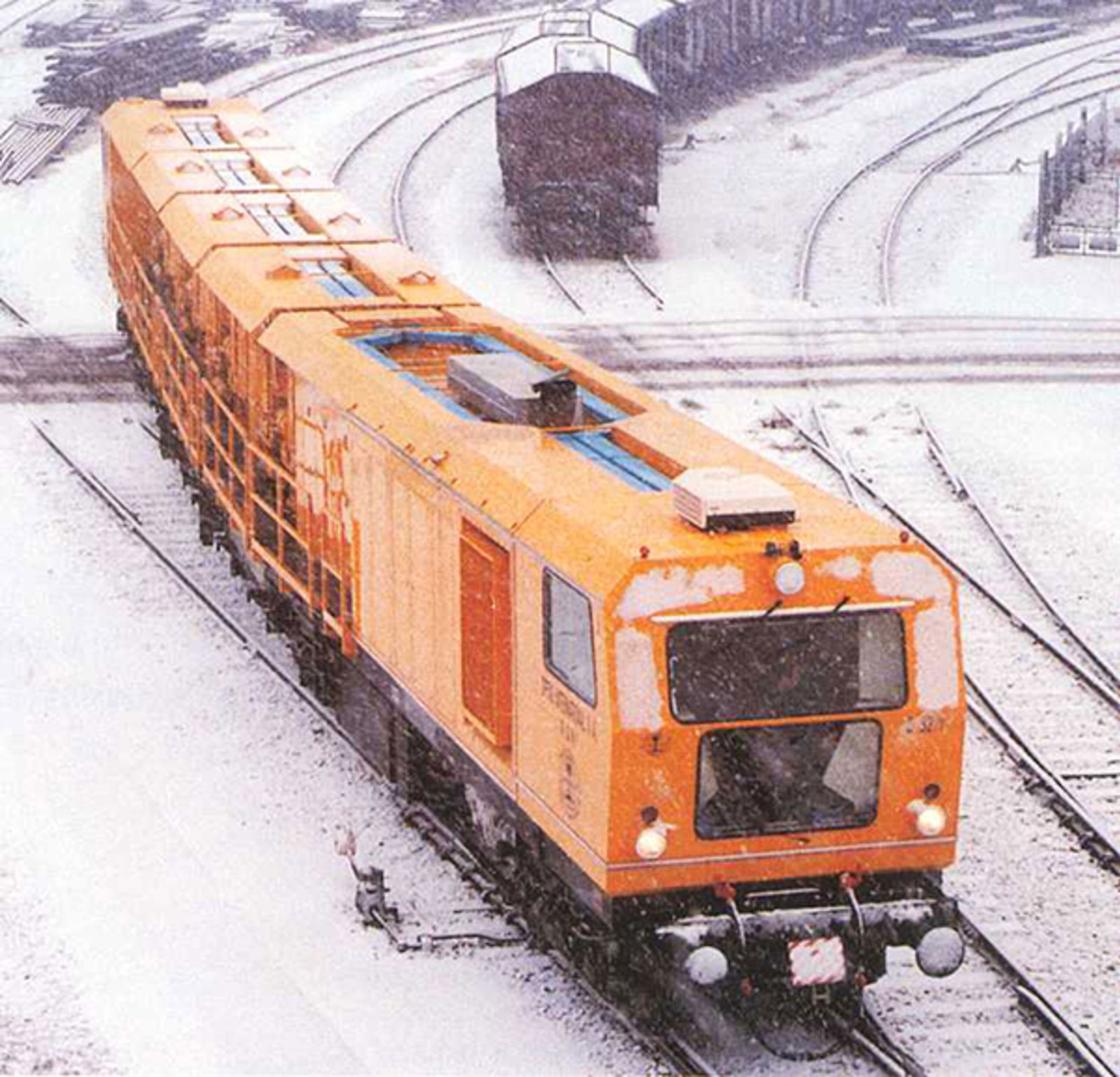 32-steners slipetog fra Speno på jernbanespor i snøvær.