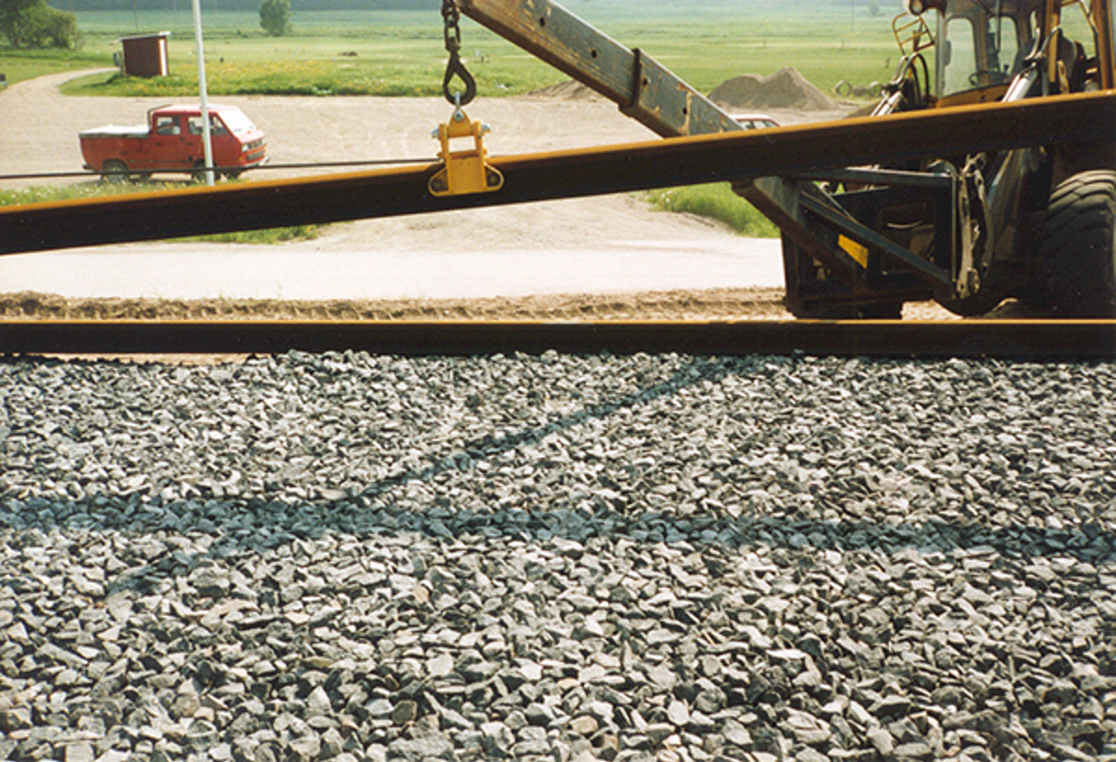 Hjullaster med spesialutstyr løfter og plasserer skinner på gruslagt sportrase.