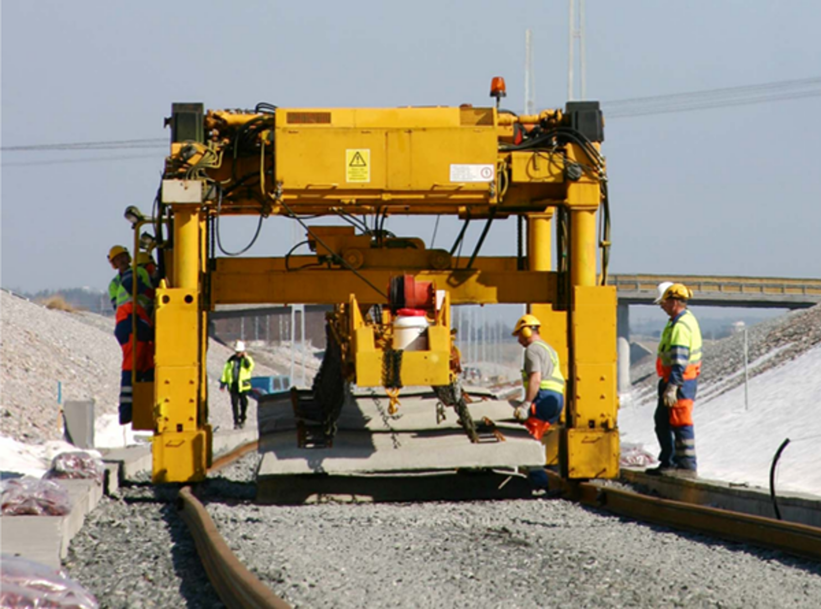 Donelli-portalkran løfter betongsviller med kjettinger og kroker under sporbygging.