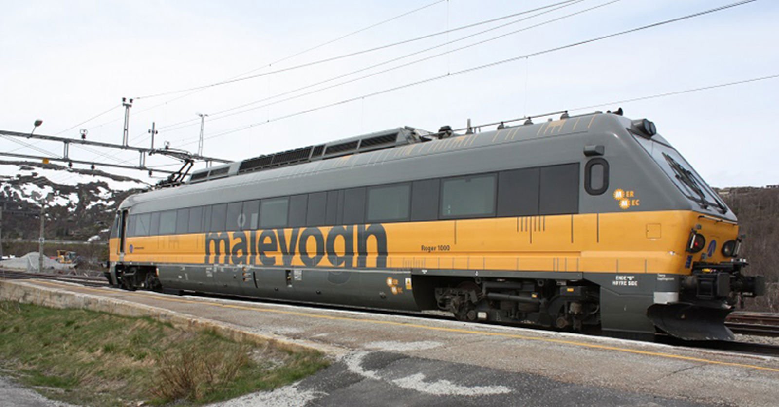 Målevogn Roger 1000 på spor med tydelig merking, fotografert i dagslys nær en plattform.