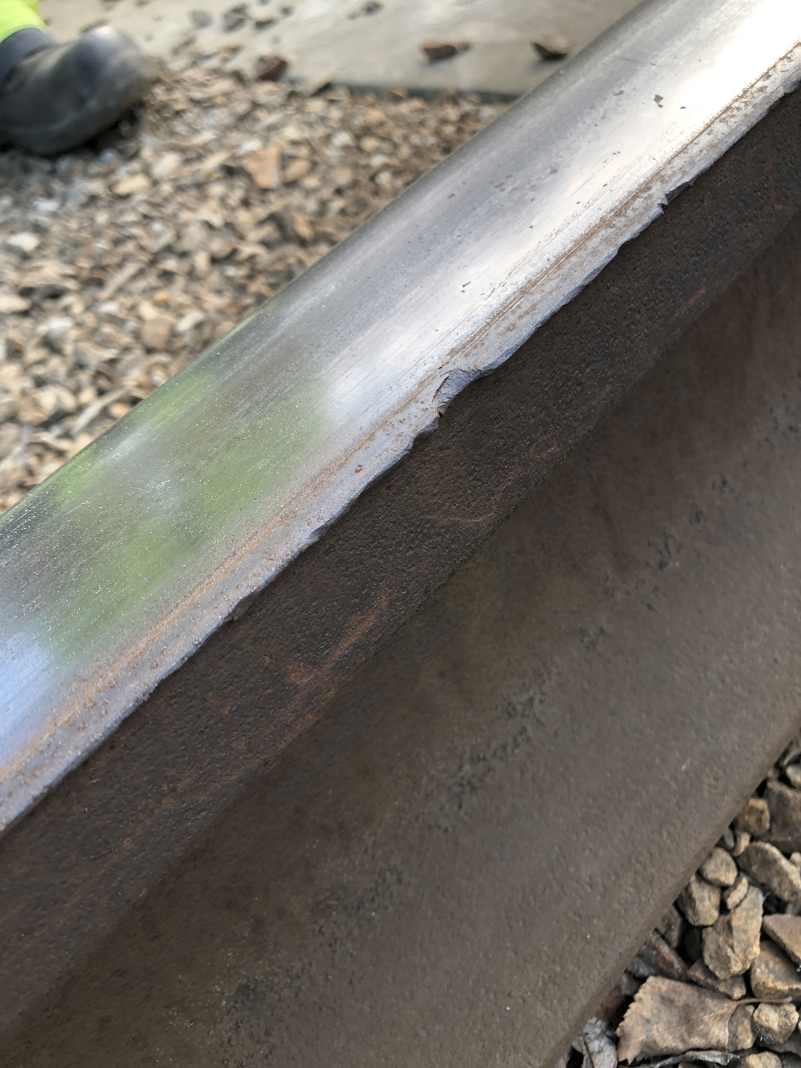 Slitt skinne med tydelig ujevn og nedslitt kjørekant, sett nærbilde fra siden i dagslys.