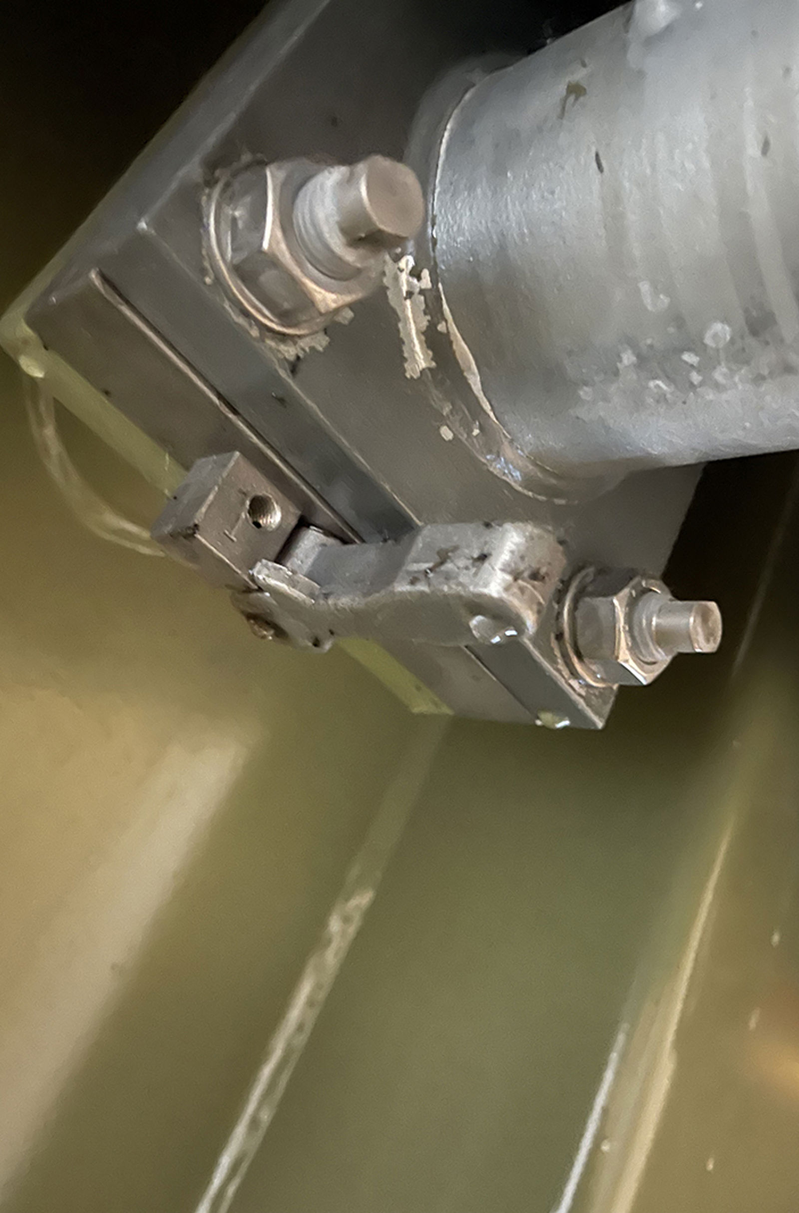 Oljelekkasje i rørovergang mellom transformatorkasse og radiator, synlig ved pakning og bolter.