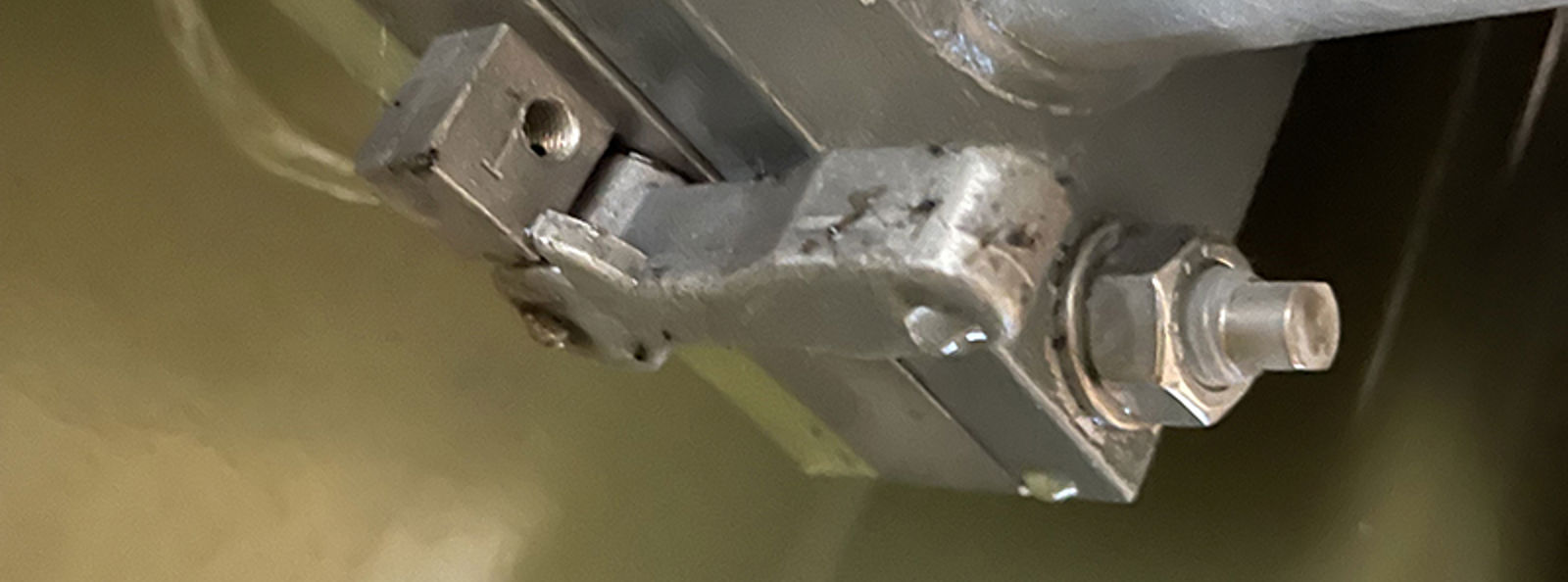 Oljelekkasje i rørovergang mellom transformatorkasse og radiator, synlig ved pakning og bolter.
