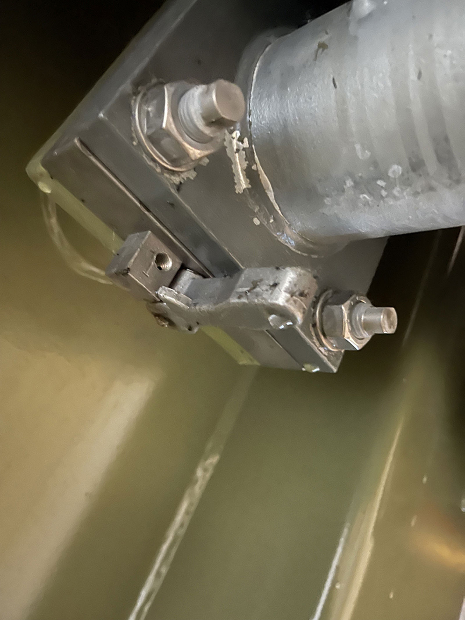 Oljelekkasje i rørovergang mellom transformatorkasse og radiator, synlig ved pakning og bolter.