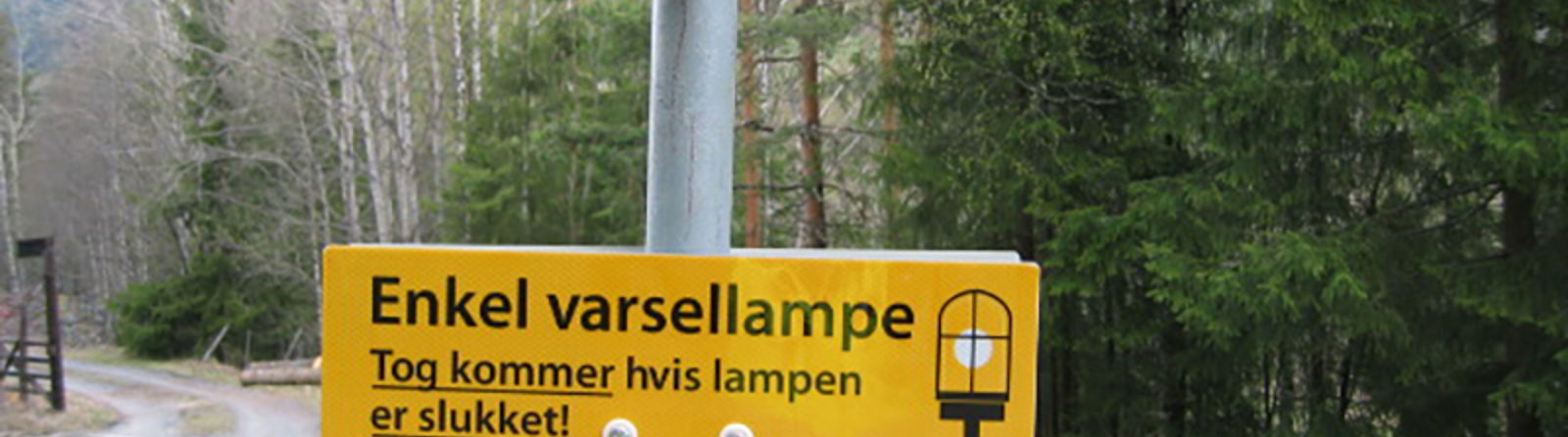 Informasjonsskilt om varsellampe ved planovergang: Tog kommer hvis lampen er slukket.