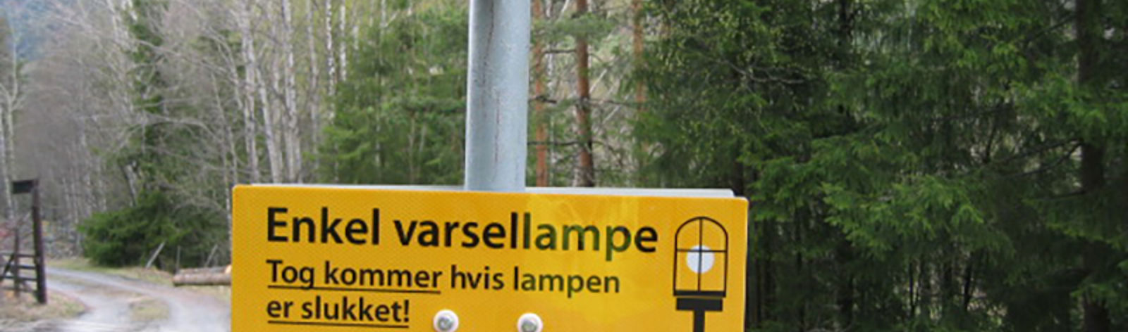 Informasjonsskilt om varsellampe ved planovergang: Tog kommer hvis lampen er slukket.