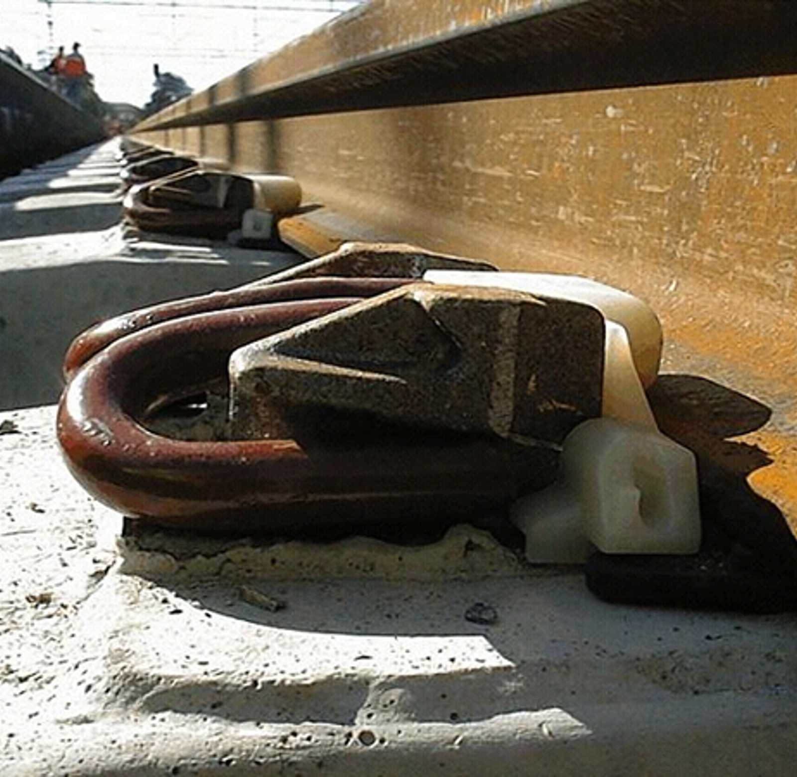 Fjærende skinnebefestigelse på betongsville med klemfjær, isolatorer og elastisk mellomlegg.