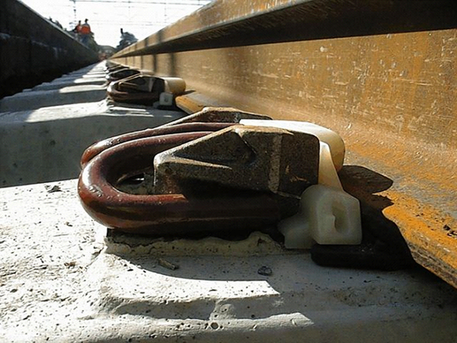 Fjærende skinnebefestigelse på betongsville med klemfjær, isolatorer og elastisk mellomlegg.