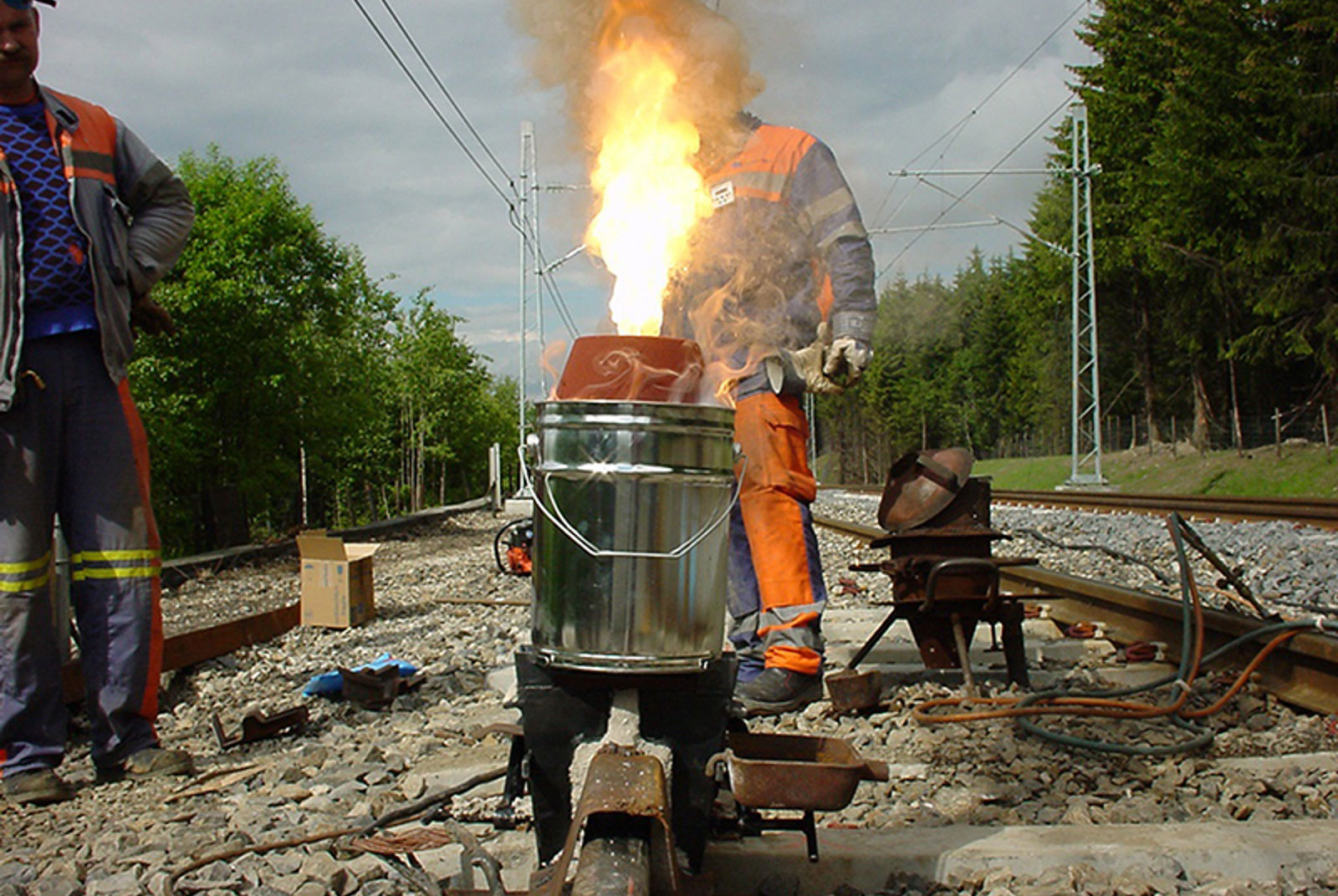 Thermit-reaksjon ved skjøtsveising av skinner, med kraftig flamme over digelen.