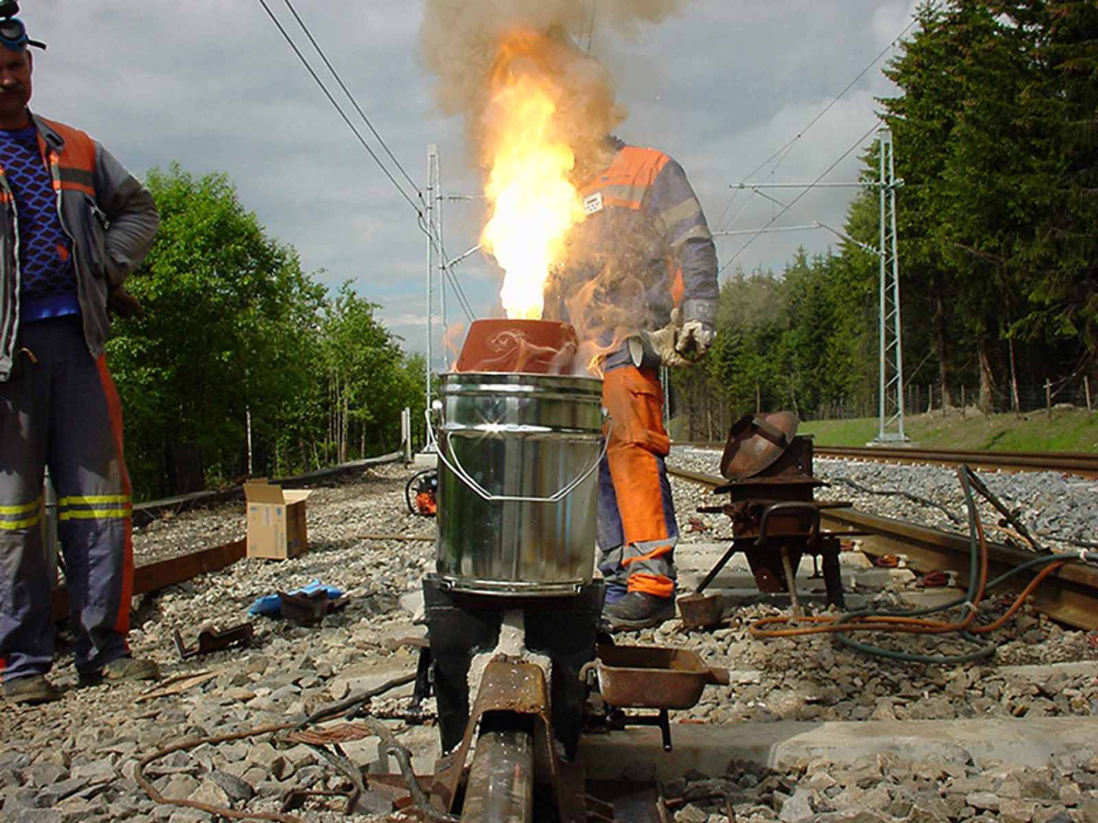 Thermit-reaksjon ved skjøtsveising av skinner, med kraftig flamme over digelen.