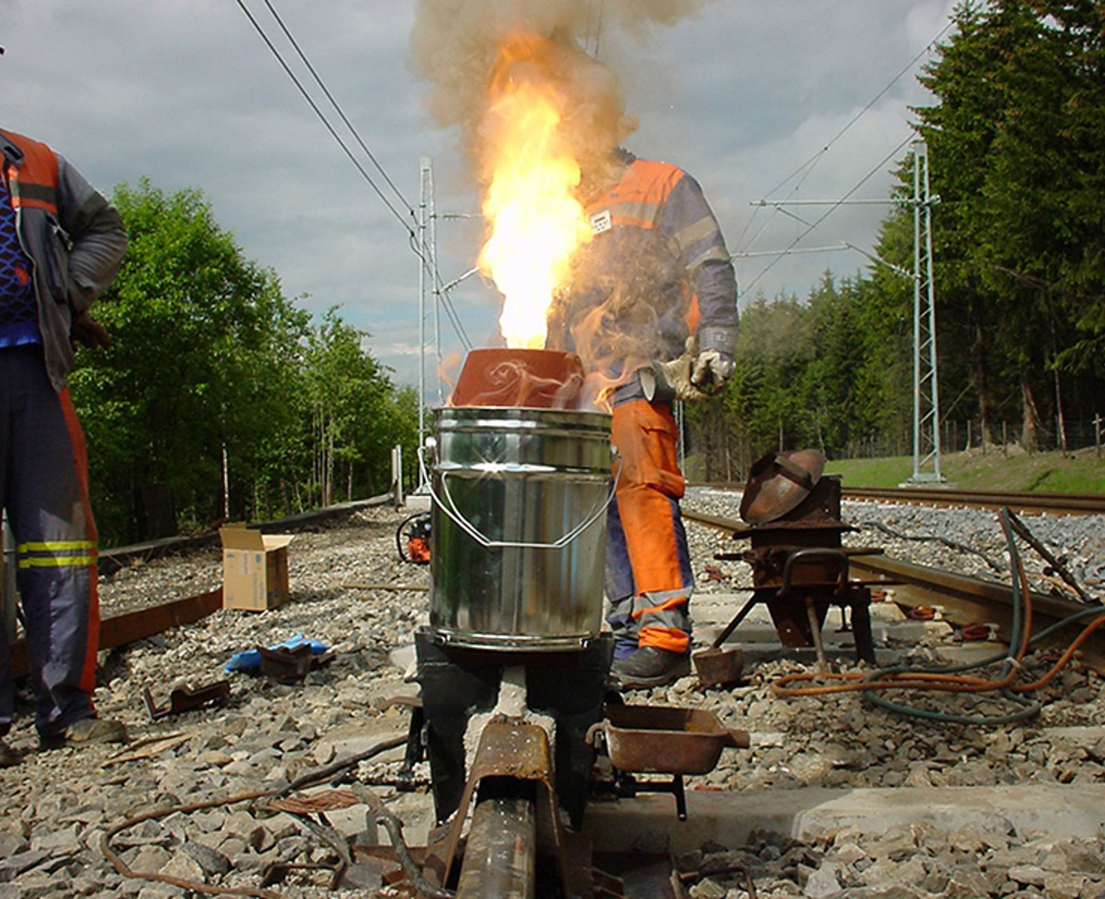 Thermit-reaksjon ved skjøtsveising av skinner, med kraftig flamme over digelen.