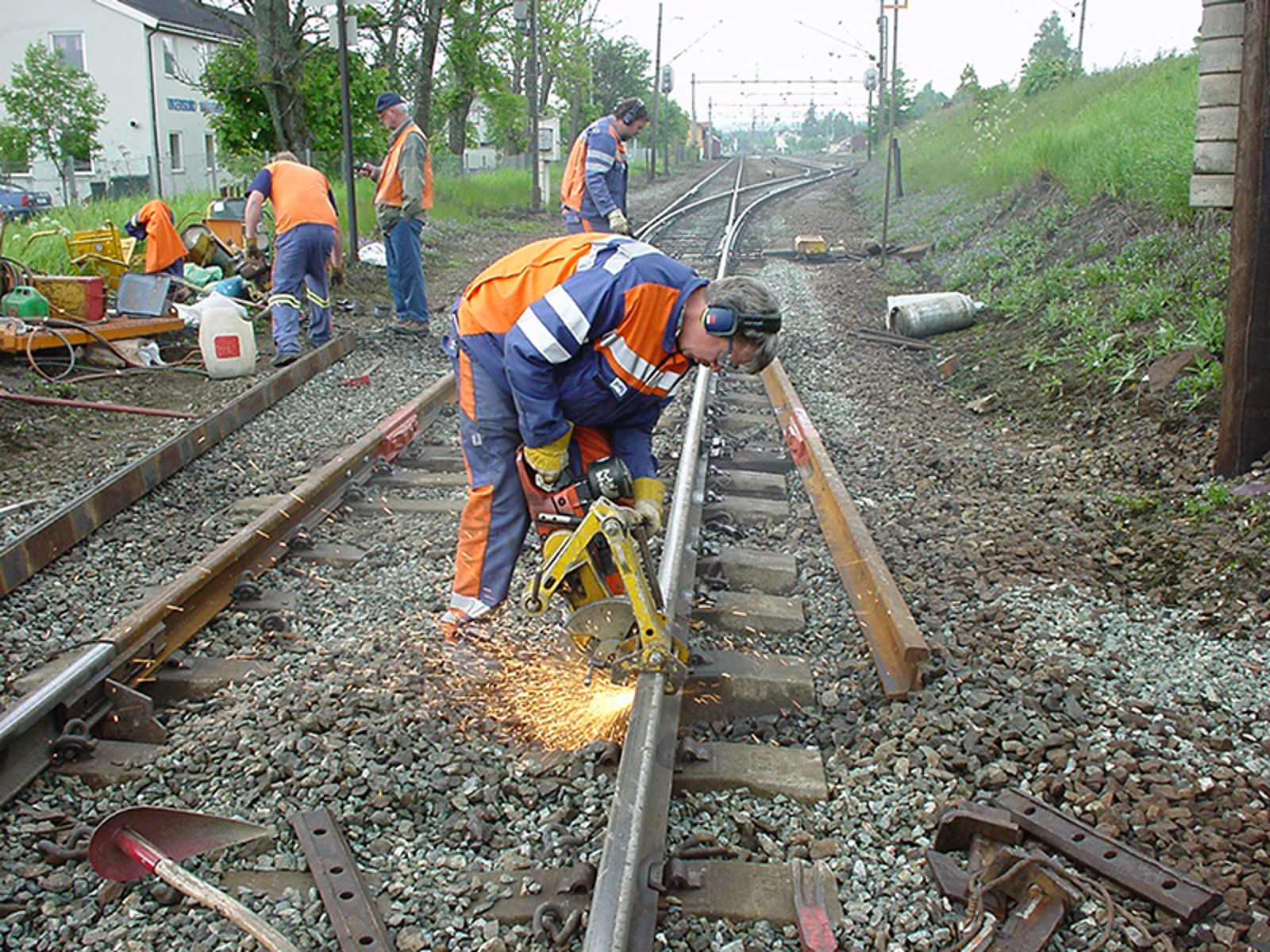 Arbeider kapper en jernbaneskinne med skinnekutter, gir renere kutt og lavere temperatur.