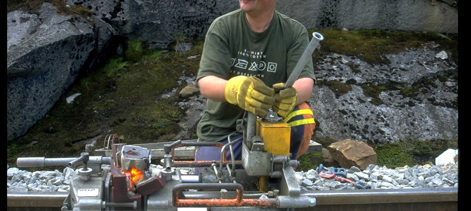 Jernbanearbeider bruker hydraulisk apparat for å skjære bort sveisevulsten på skinnehodet.