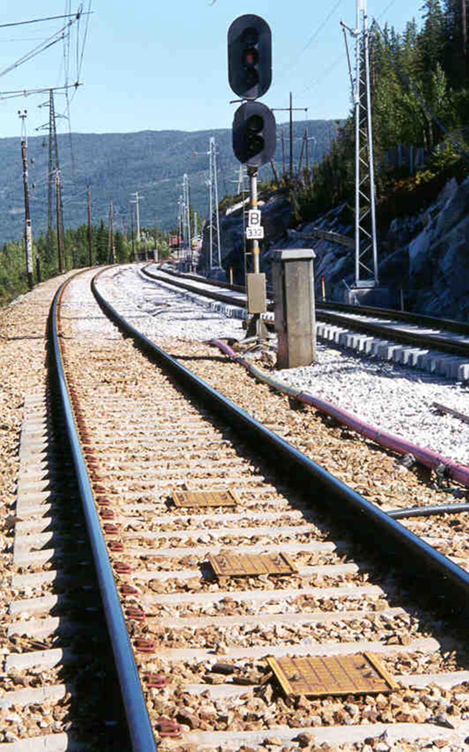 Balisegruppe i sporet foran hovedsignal med flere baliser montert mellom skinnene.
